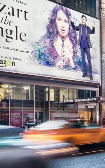 Billboard advertisement for "Mozart in the Jungle" on Amazon, with taxi blurred in motion on city street.