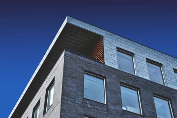 Modern apartment building with dark gray exterior against blue sky.